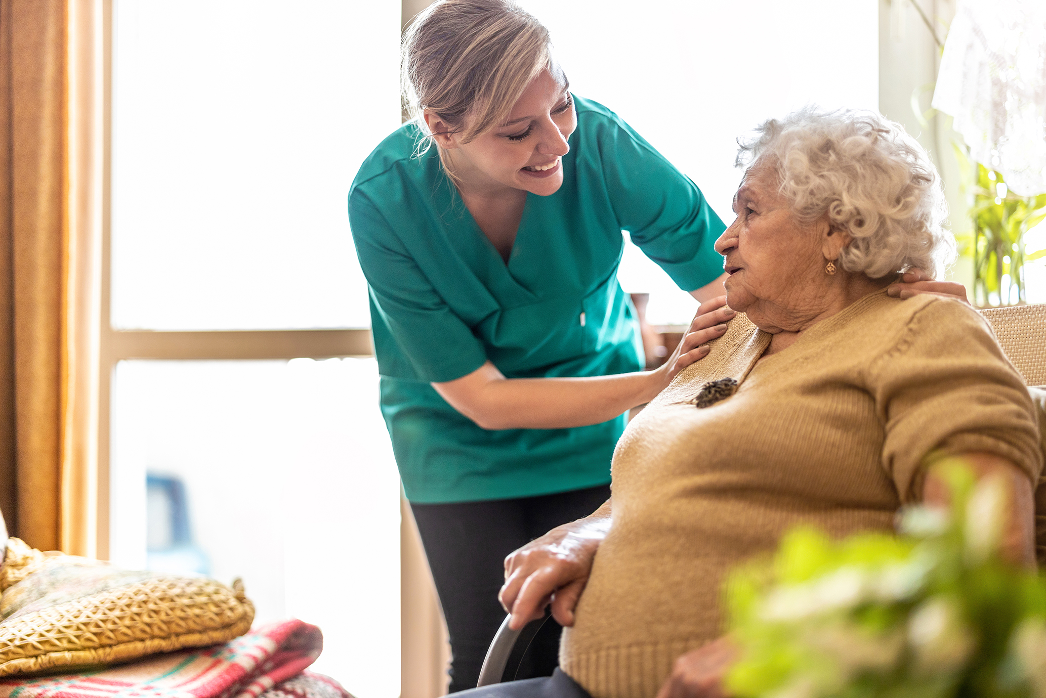 Older woman sitting getting assistance from a female healthcare worker